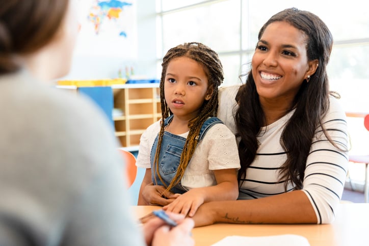 A mother and child meet with a teacher