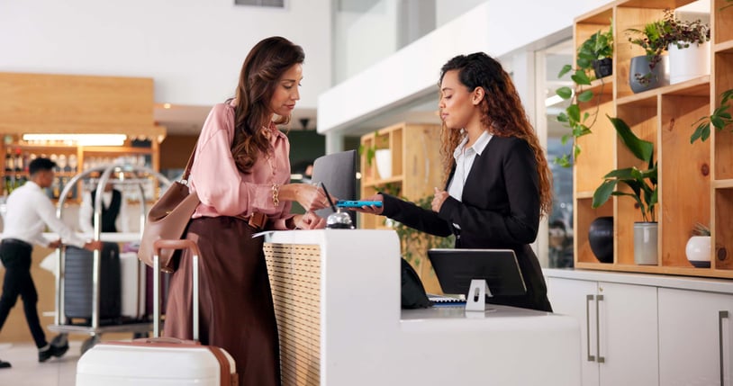 A hotel receptionist helps a customer with the help of an interpreter on the phone.