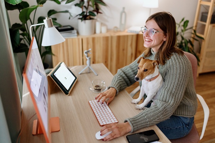 Woman sitting with dog in front of computer reviewing business document