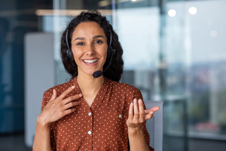An interpreter smiles as she helps a client over the phone.