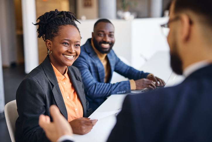 A woman smiles as she feels understood during a meeting supported by an in person interpreter