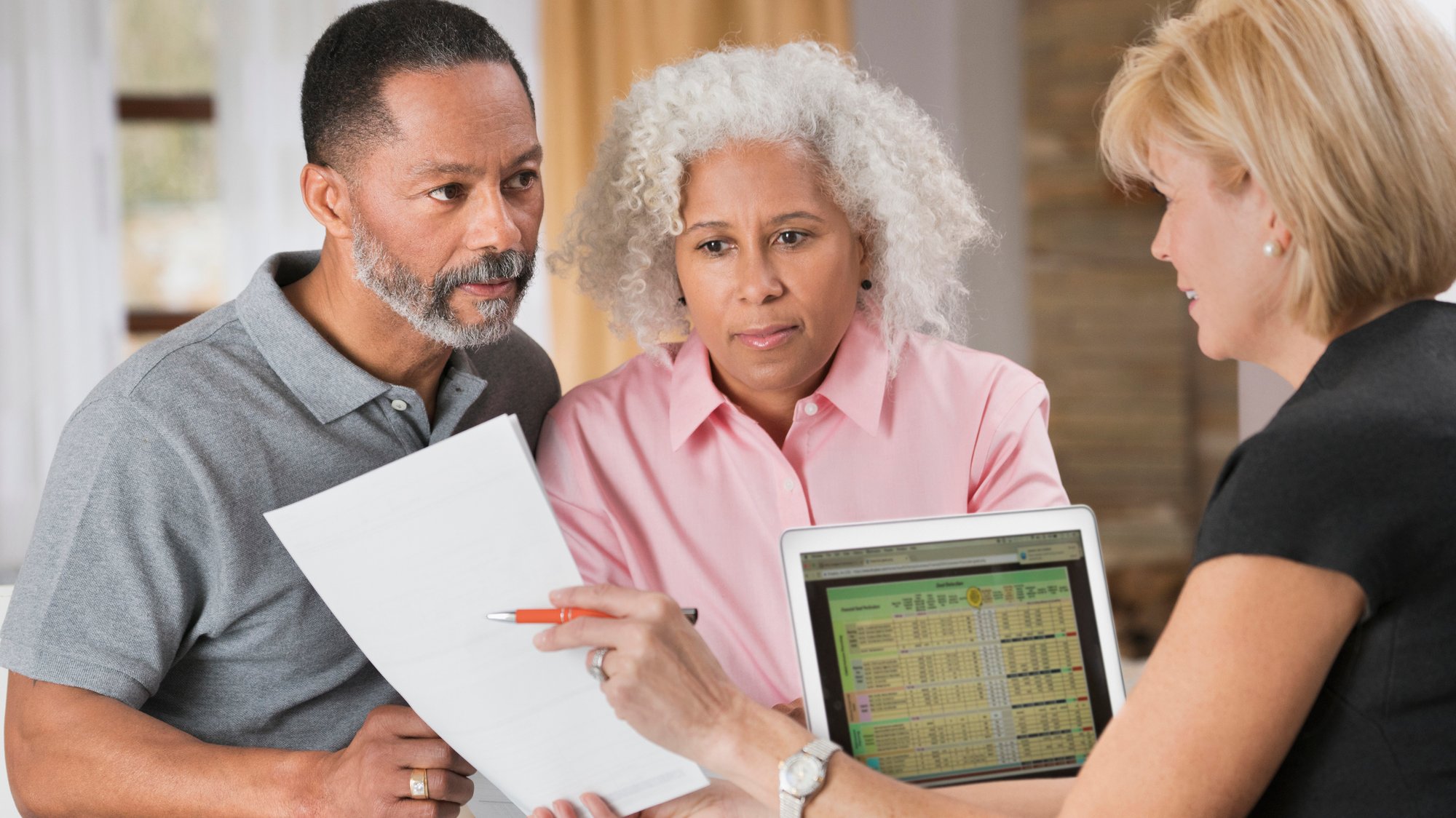 A couple looks concerned as they meet with a banker without an interpreter.