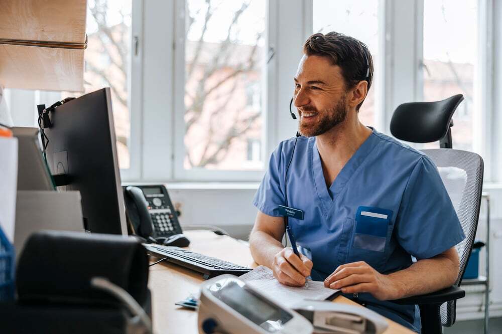 A healthcare worker speaks to a patient through an interpreter over the phone.