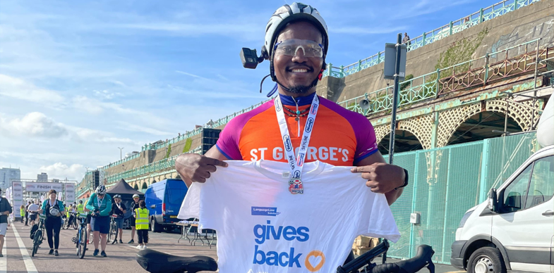A man holds up a LanguageLine Gives Back shirt