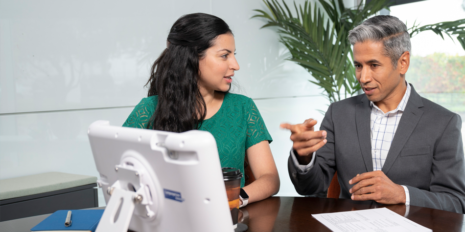 A businessman points out the interpreter on a LanguageLine desktop display for an LEP customer beside him.