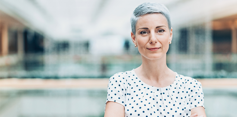 A serious woman stands with her arms crossed