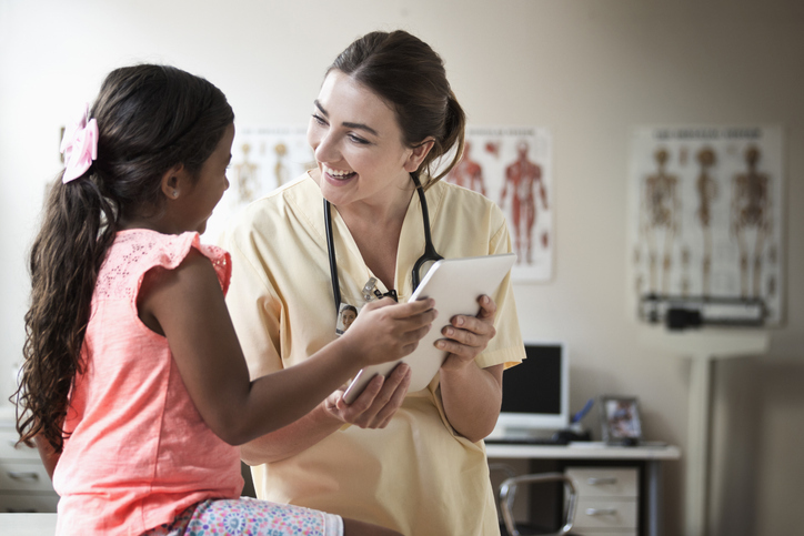 A doctor and young patient are supported by an interpreter in a video call.