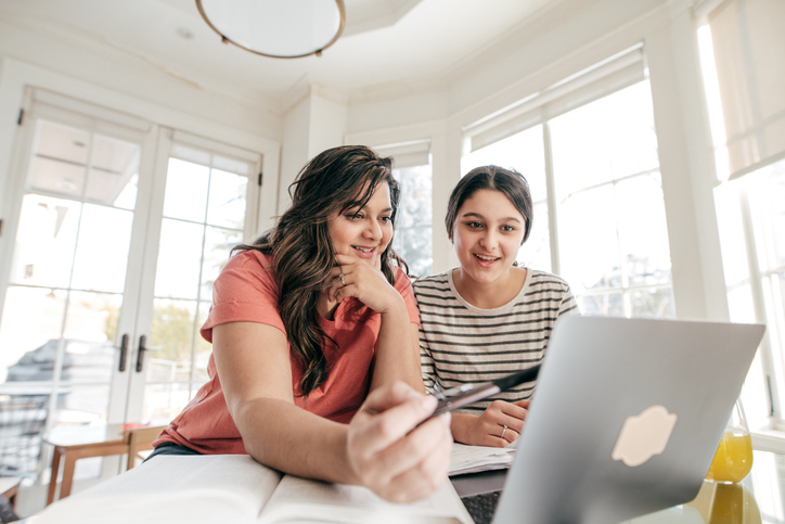 Two high school girls meet with their teacher and an interpreter online.