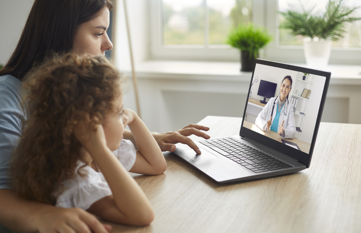 A mother and daughter talk to a doctor through an interpreter during a telehealth call.