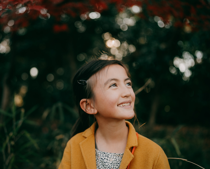 A young girl smiles while out in nature