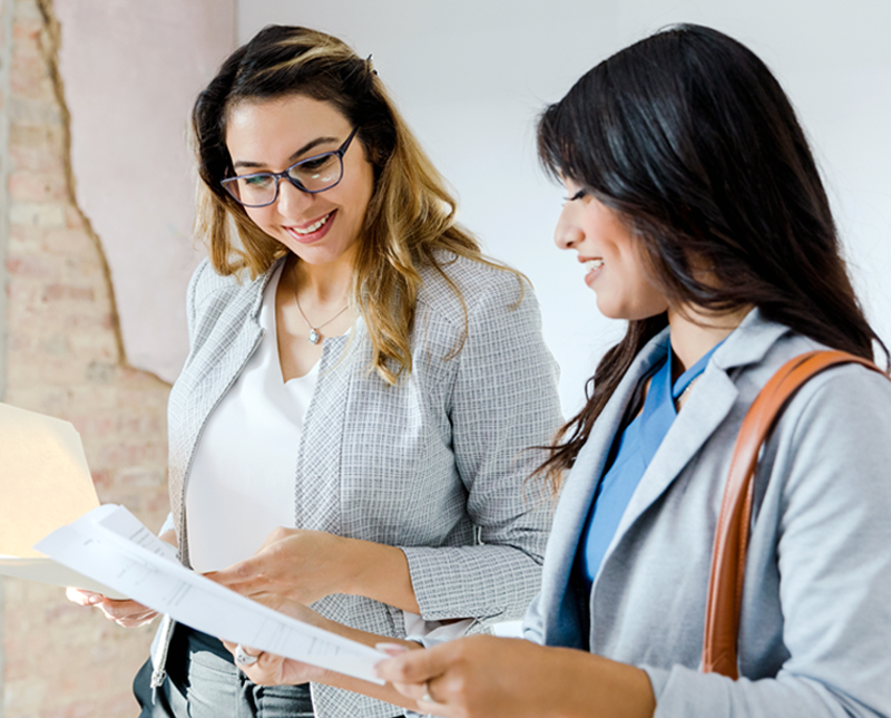 Two women share interpretation service training documentation with a smile.