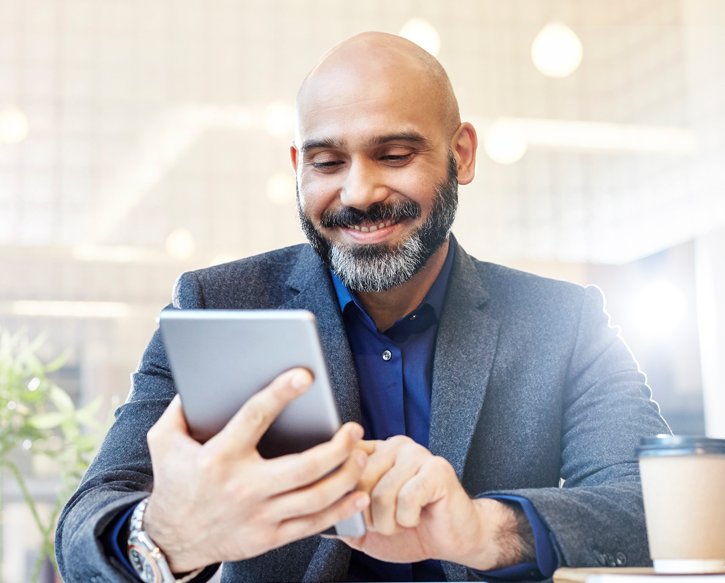A man smiles as he looks at his phone.